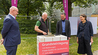 Bild zeigt wie Grundstein nach Einlegen der Zeitkapsel verputzt wird (vl.n.r.): Jörg Franzen, Vorstandsvorsitzender GESOBAU AG, Polier Herr Hannemann, Christian Gaebler, Senator für Stadtentwicklung, Bauen und Wohnen, Julia Dahlhaus, Geschäftsführerin DMSW Architekten.