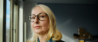 Innenaufnahme zeigt eine MItarbeiterin der GESOBAU, die selbstbewusst lächelnd in die Kamera schaut.