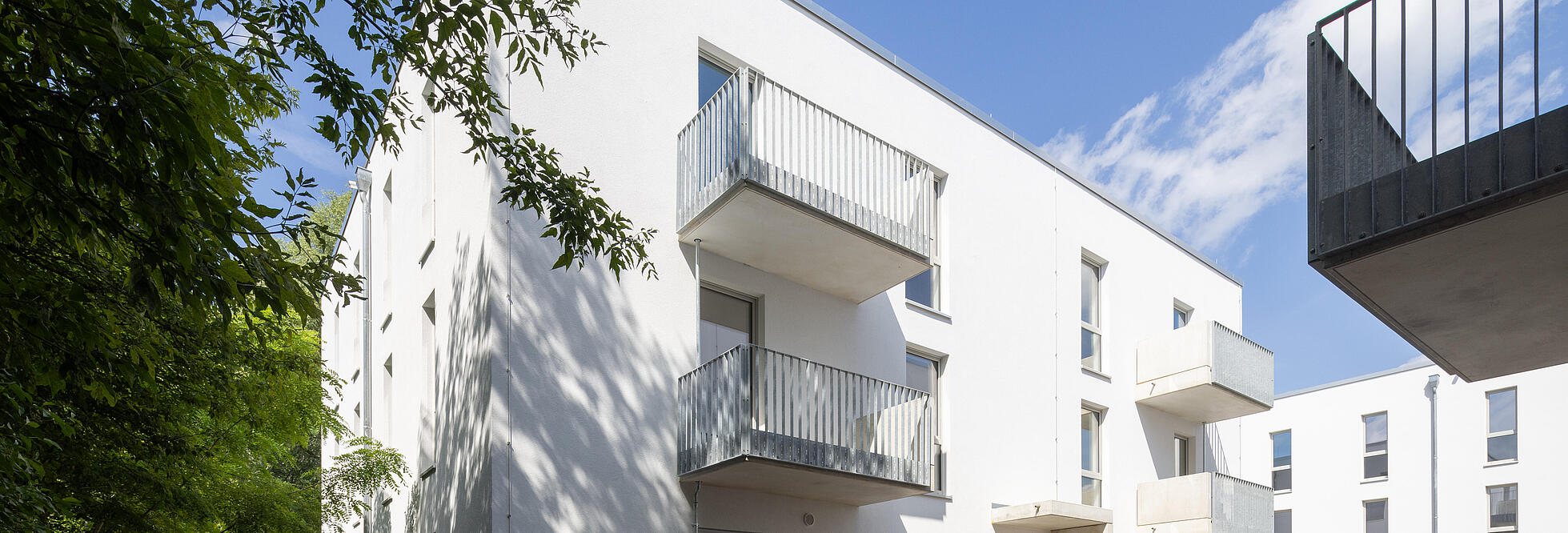 Außenaufnahme zeigt ein frisch fertiggestelltes Mehrfamilienhaus, bzw. eine mobile Unterkunft für Geflüchtete.