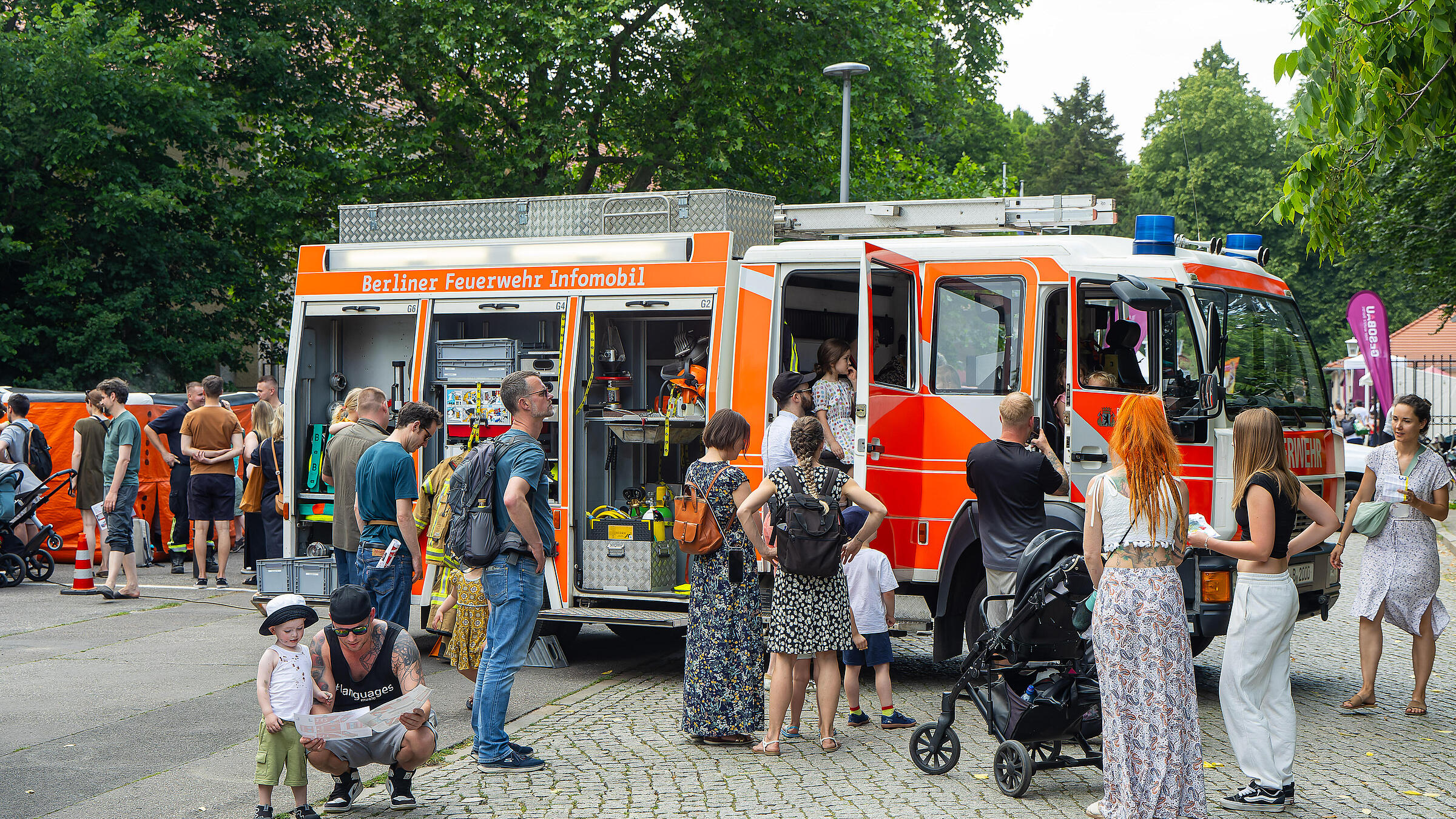 Außenaufnahme zeigt Interessierte beim Betrachten eines Gruppenlöschfahrzeugs der Freiwilligen Feuerwehr Pankow. 