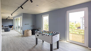 Innenaufnahme zeigt einen Kicker und bodentiefe Fenster.