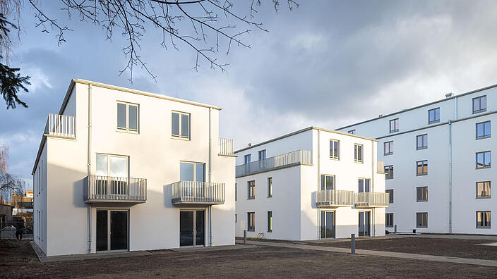 Außenaufnahme zeigt zwei dreigeschossige, neu gebaute Wohnhäuser.