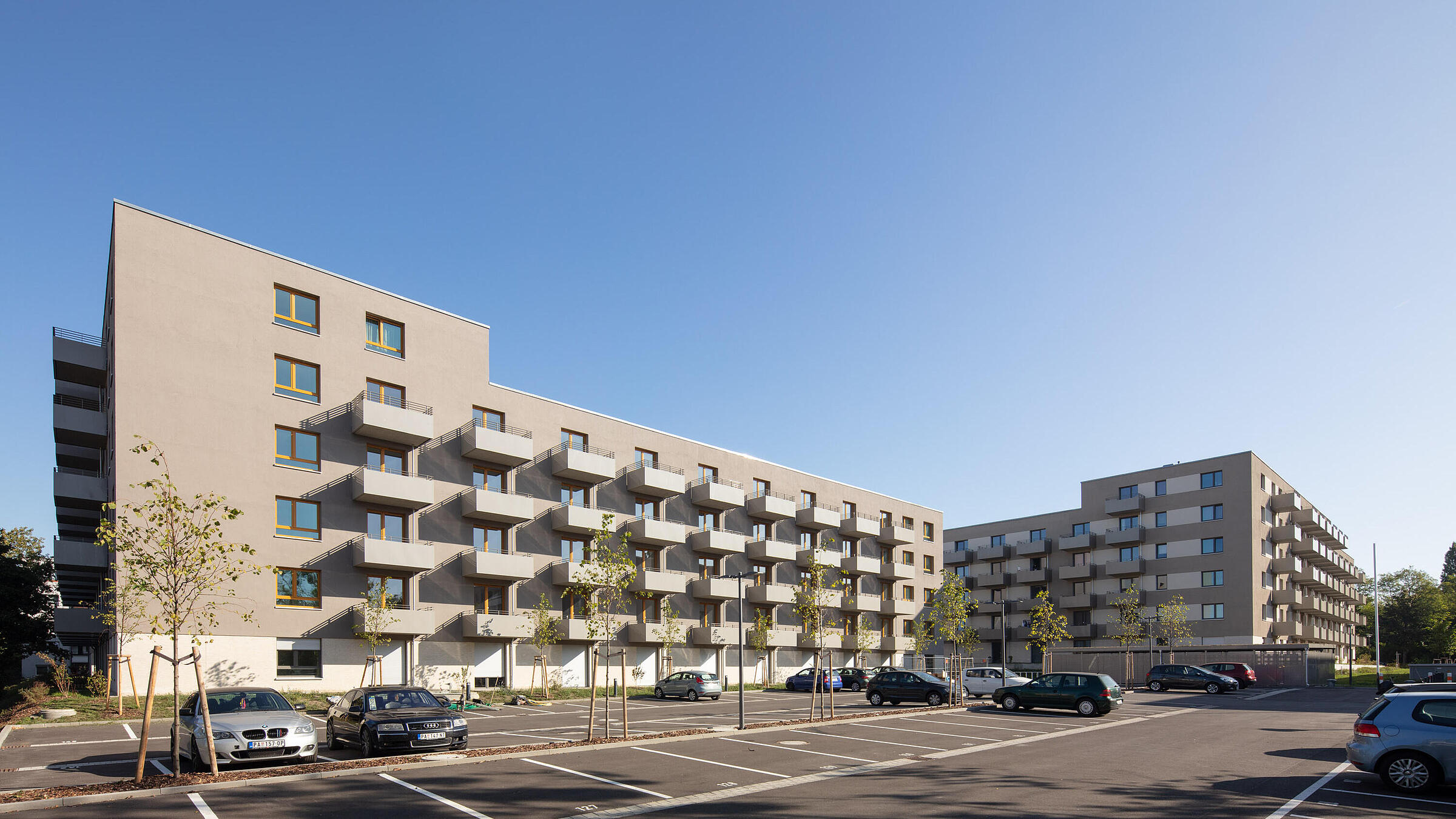 Blick auf Gebäude mit Parkplatz im Vordergrund.