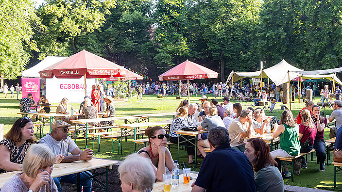 Menschen sitzen auf der Festwiese.