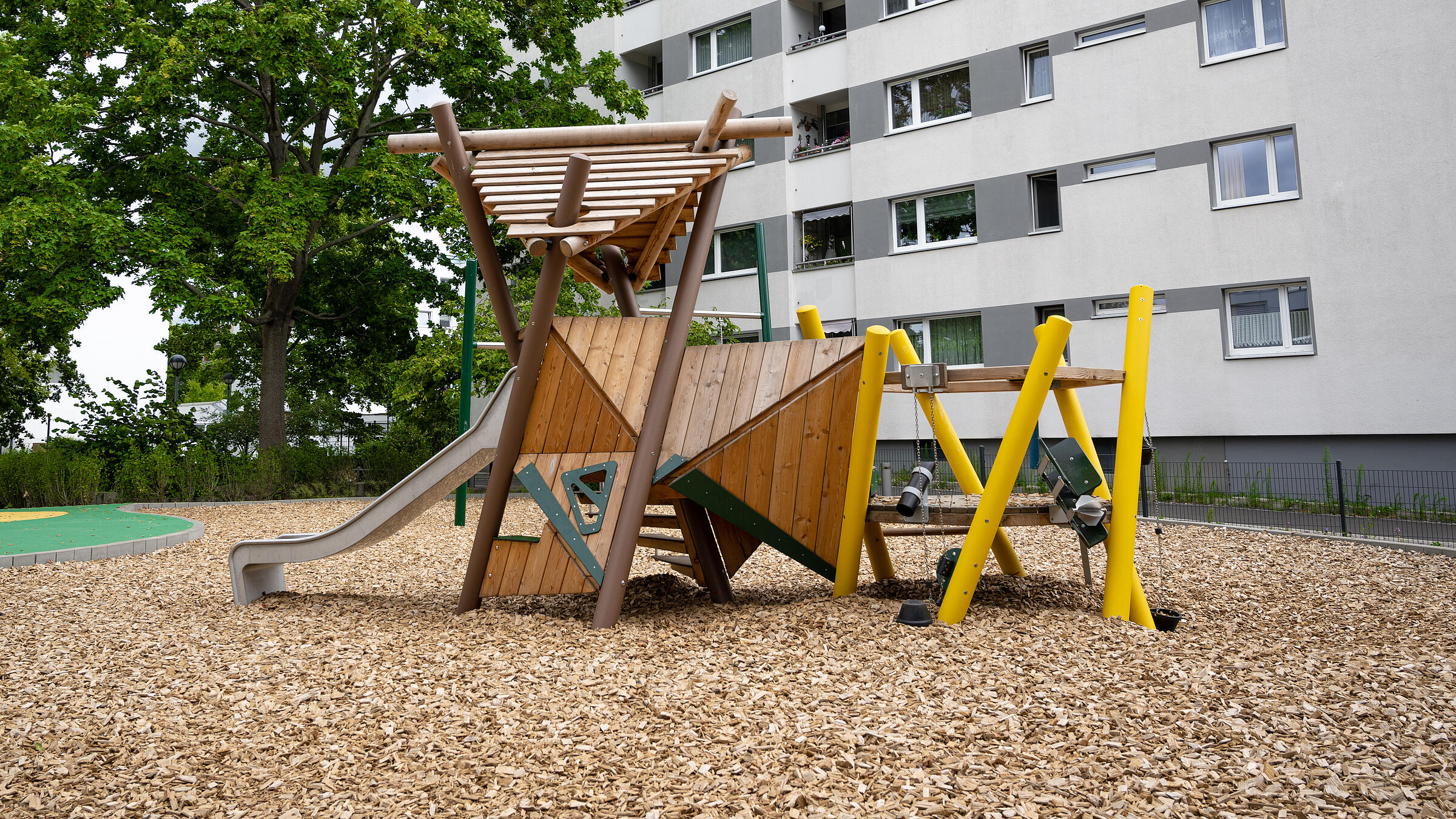 Außenaufnahme neuer Spielplatz am Wilhelmsruher Damm. Im Hintergrund Mehrfamilienhaus.