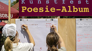 Außenaufnahme zeigt das Outdoor-Poesie-Album, bei dem Besucher*innen ihre eigene Lyrik anheften konnten.