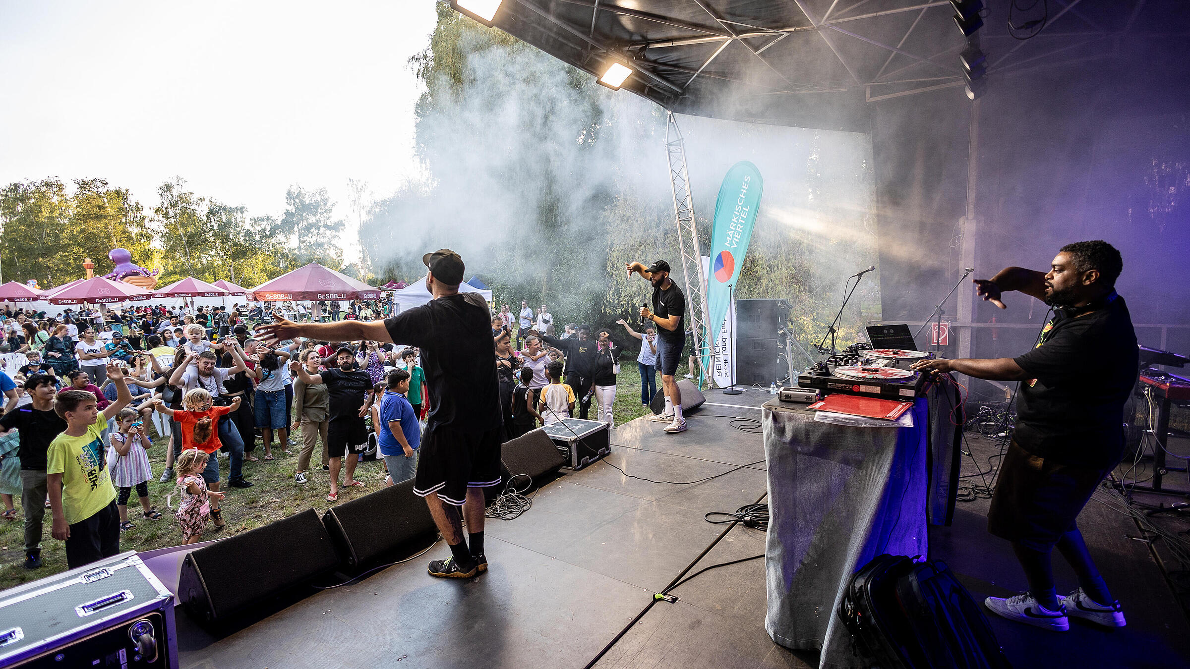 Außenaufnahme zeigt Musiker auf einer in Nebel gehüllten Bühne mit begeistertem Publikum.