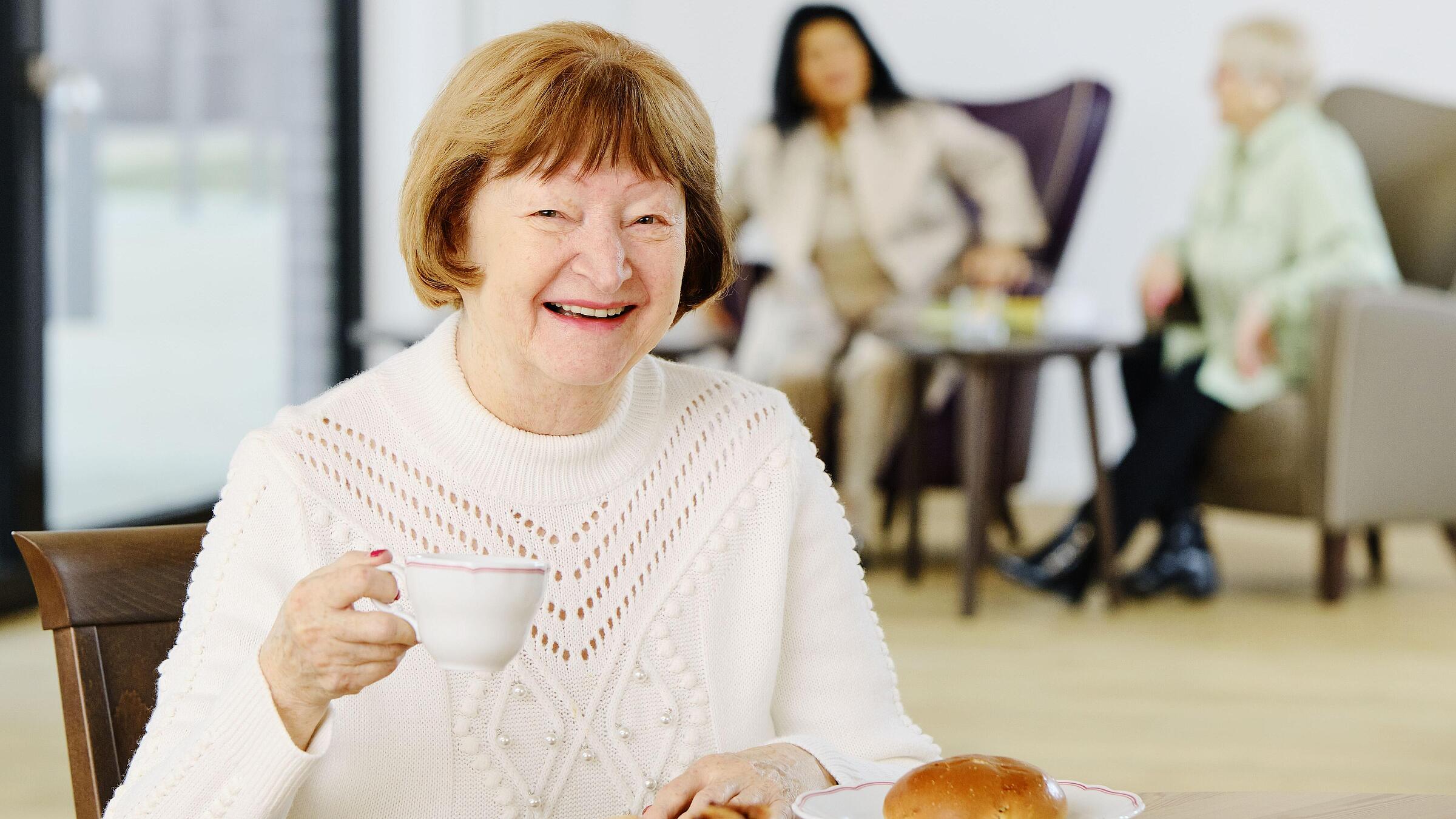 Seniorin beim Frühstück im Gemeinschaftsraum