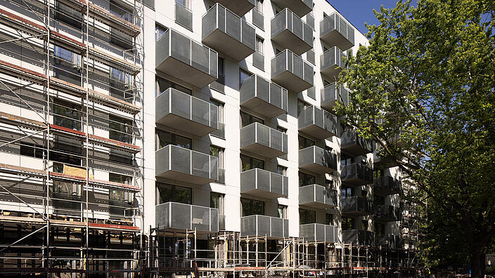 Außenaufnahme zeigt die teilweise abgerüstete Fassade in der Armenischen Straße. Rechter Hand gut erkennbar die grauen Balkone, die sich gut von der weißen Fassade abheben.  