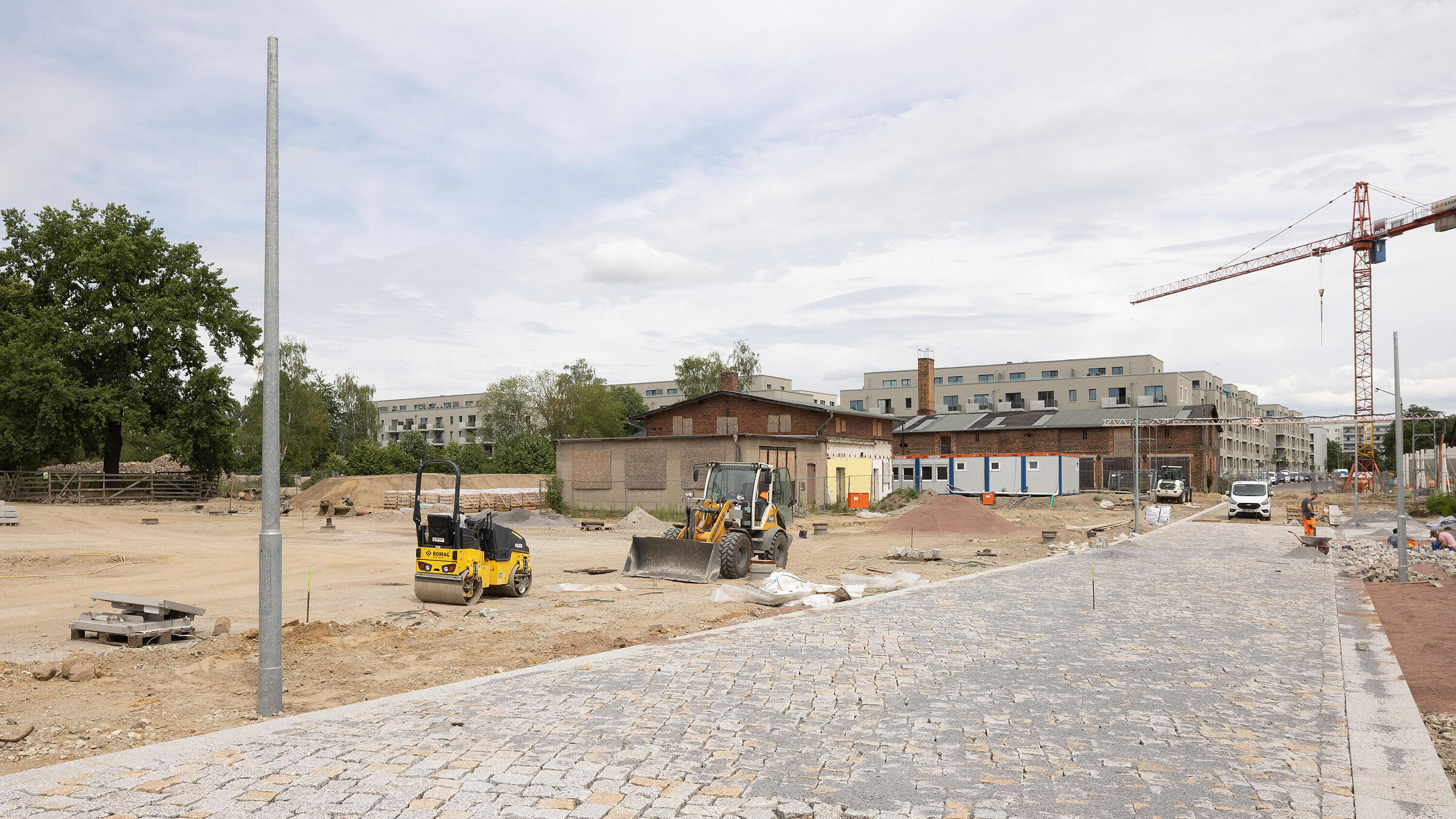 Stadtplatz im Quartier Stadtgut Hellersdorf: eine Straße aus Pflastersteinen führt noch durch eine Baustelle