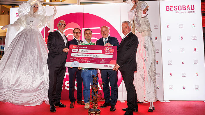 Jörg Franzen, Andreas Kraus, Bob Hanning, Kai Wegner und Christian Wilkens halten den symbolischen Spendenscheck für 125 neue Stadtbäume in Berlin