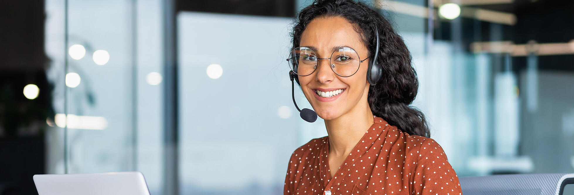 Junge Frau an einem Laptop mit Headset 