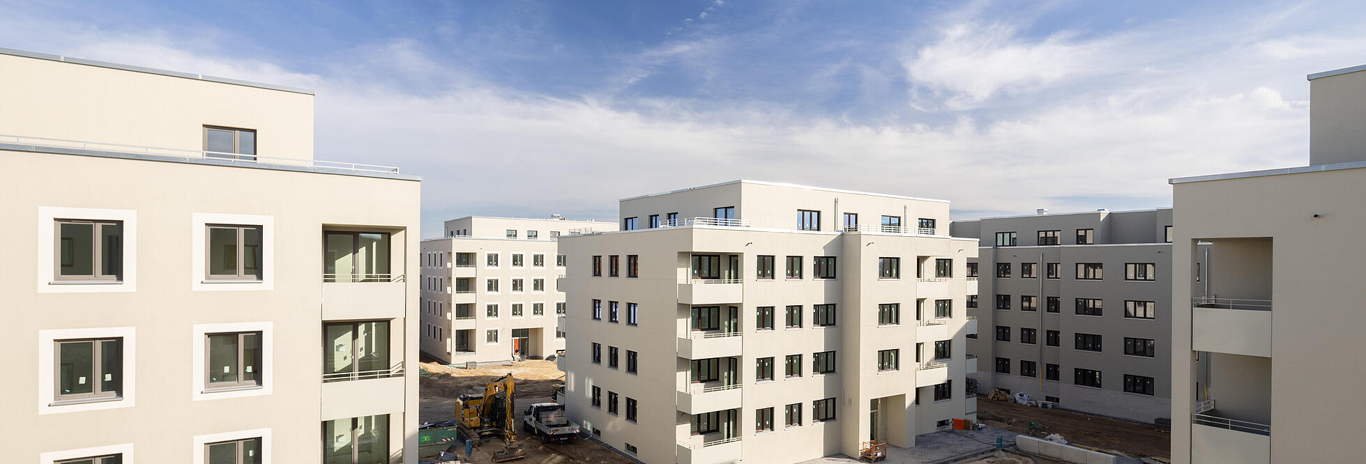 Blick in den Innenhof einer modernen Wohnanlage mit mehreren Neubauten, die sich in der Baufertigstellung befinden