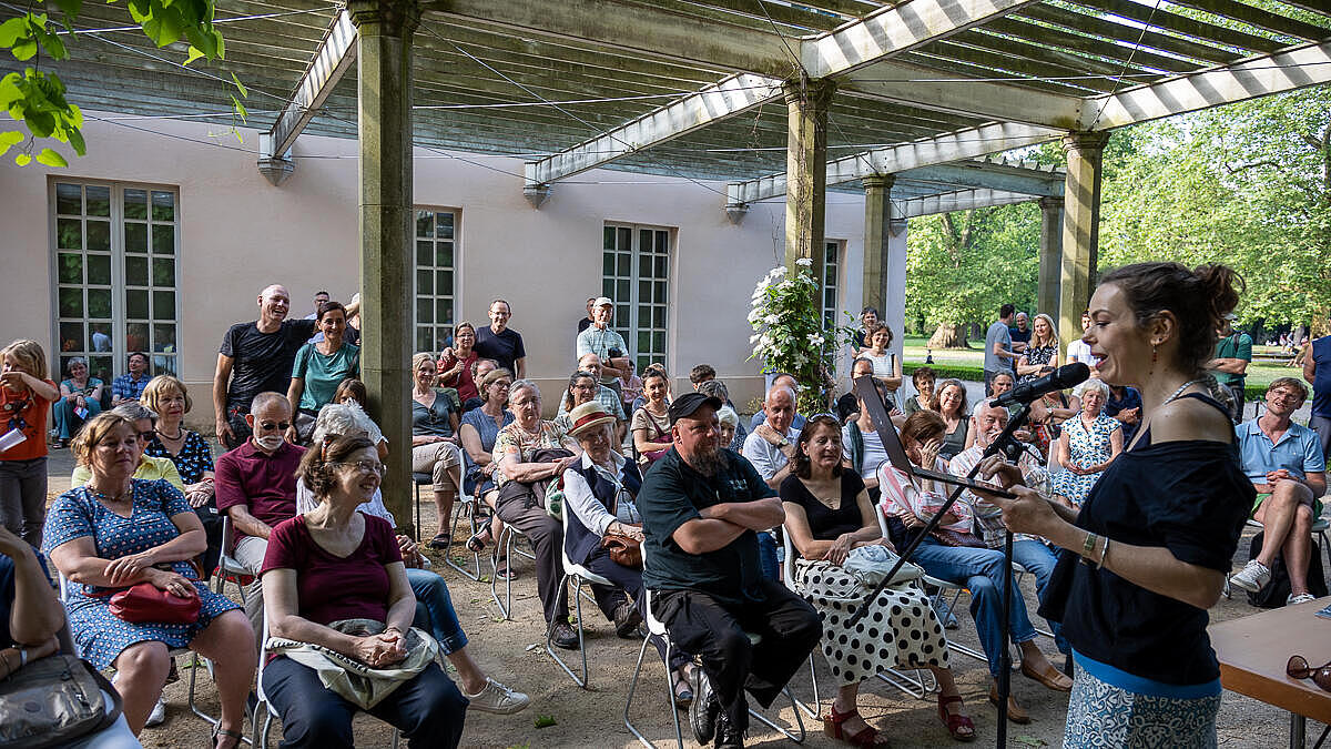 Außenaufnahme zeigt Publikum und Vortragende im Lesepavillon.