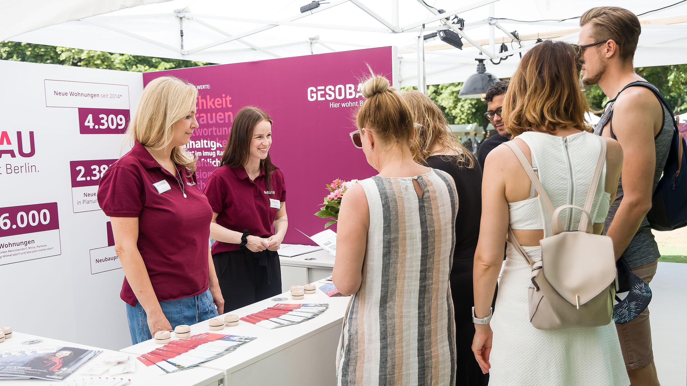 Außenaufnahme zeigt GESOBAU Mitarbeiter*innen im Gespräch mit Besucher*innen.