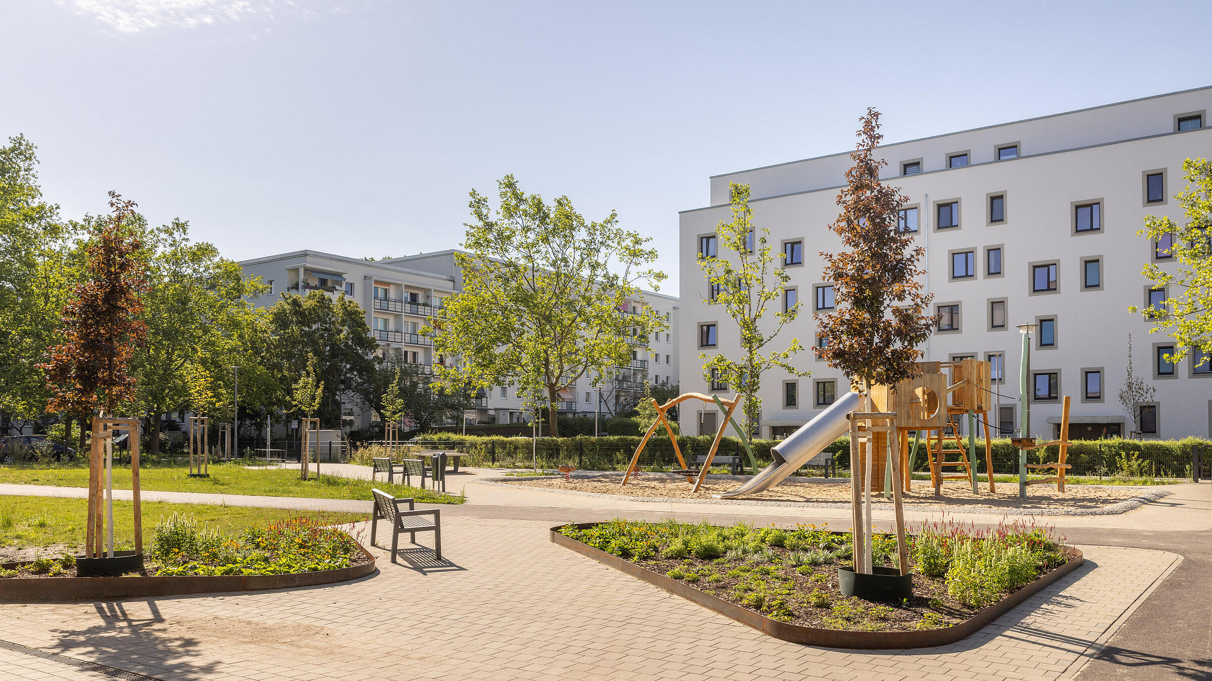 Stadtpark im Quartier Stadtgut Hellersdorf: Blick auf die Wege und Grünflächen, im Hintergrund sieht man einen Spielplatz und ein modernes Wohnhaus