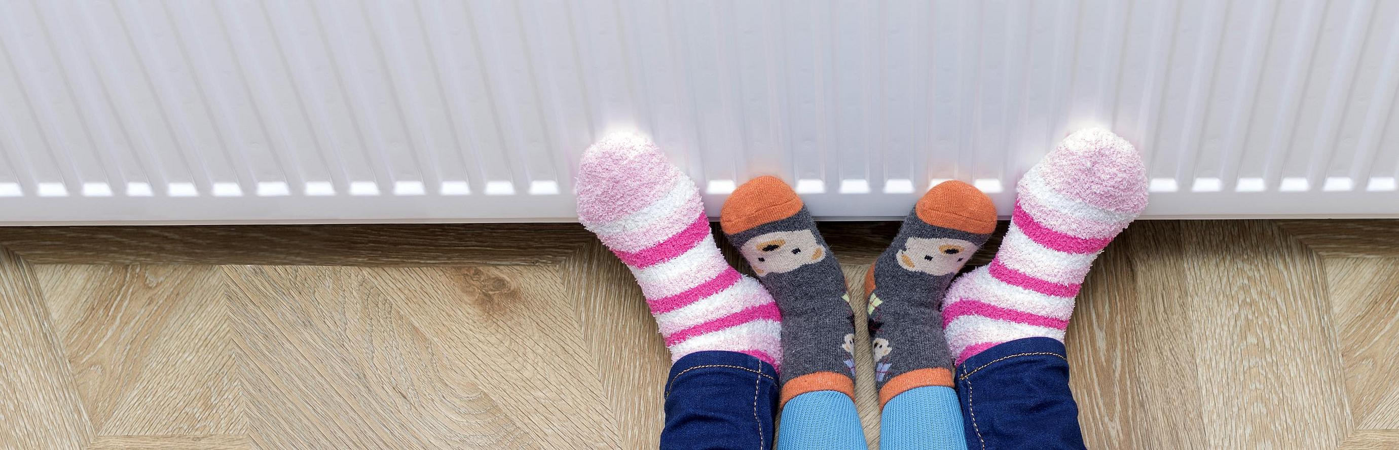 Füße wärmen sich an einem Heizkörper