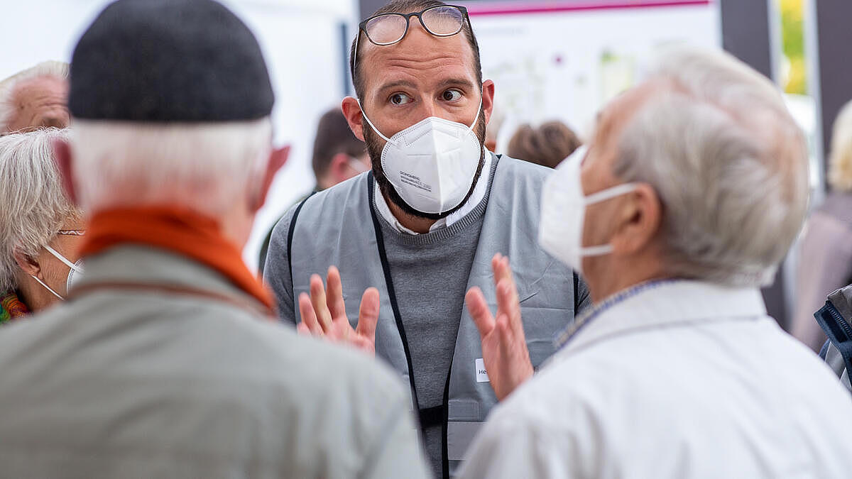 Herr Eicher von der GESOBAU im Gespräch mit einer Gruppe älterer Mieter*innen.