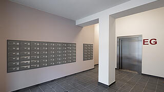 Innenaufnahme: Eingangsbereich für Mieter*innen im Wilhelmsruher Damm 142, Lift und Briefkästen.