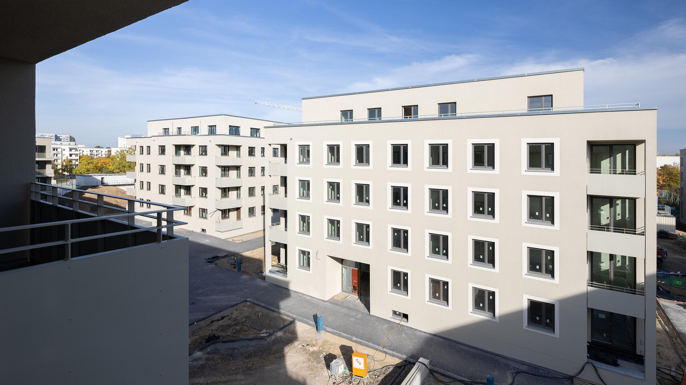 Blick vom Balkon auf ein modernes, helles mehrstöckiges Wohnhaus im Bau