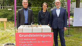 Bild zeigt Redner*innen bei Grundsteinlegung am Hamburger Platz am 17. Juni 2024 hinter dem Grundstein stehend (v.l.n.r): Christian Gaebler, Senator für Stadtentwicklung, Bauen und Wohnen, Julia Dahlhaus, Geschäftsführerin DMSW Architekten, Jörg Franzen, Vorstandsvorsitzender der GESOBAU.