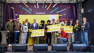 Junge Musikerinnen und Musiker erhalten Geldschecks, Pokale und Blumen auf der Bühne