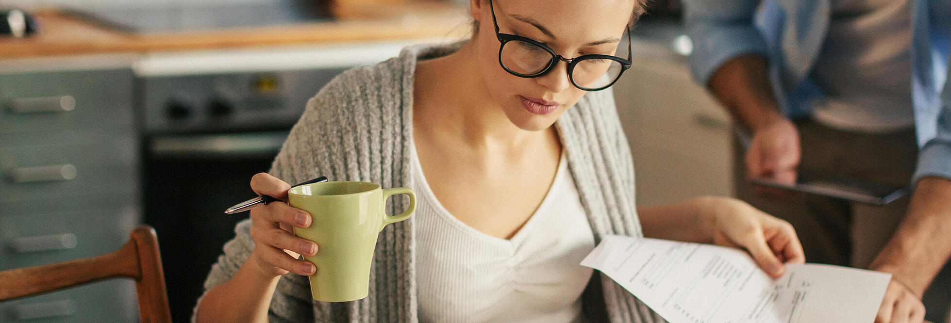 Frau mit Kaffeetasse und Unterlagen 