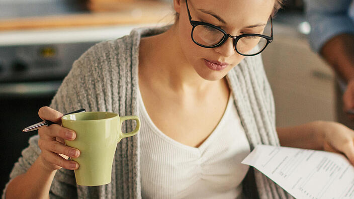 Frau mit Kaffeetasse und Unterlagen 