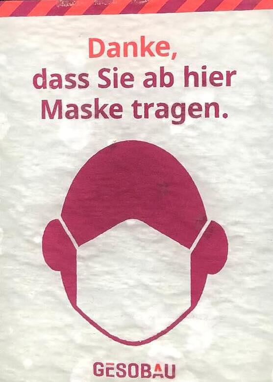 Sticker mit der Aufschrift "Danke, dass Sie ab hier Maske tragen" und einem Kopf mit Maske in den GESOBAU-Farben.