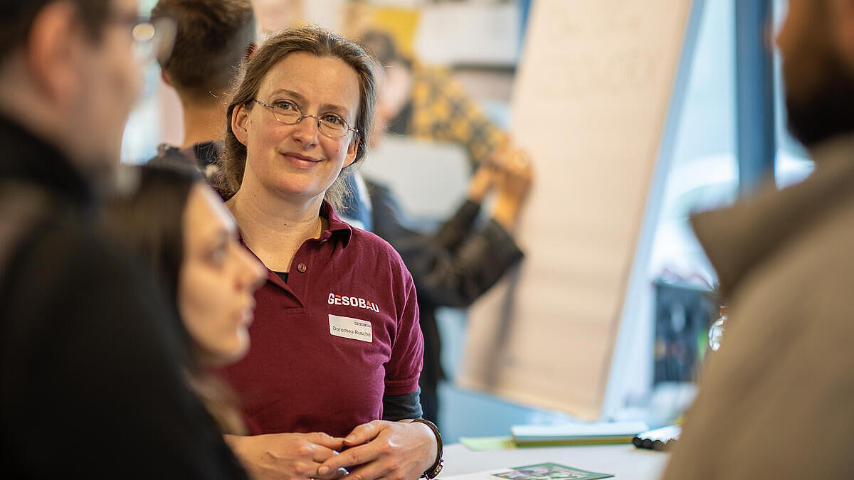 Innenaufnahme zeigt die Nachhaltigkeitsbeauftragte der GESOBAU, Dorothea Busche, im Gespräch mit Mieter*innen. 