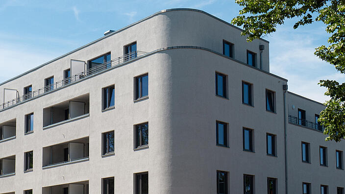 Außenaufnahme zeigt die Fassade des fertigen Wohnhauses mit der markanten abgerundeten Ecke.