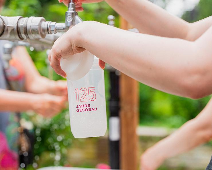 Nahaufnahme einer sich im Auffüllen befindlichen Wasserflasche mit dem GESOBAU Logo darauf.