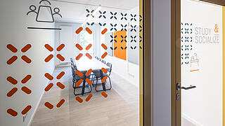 Innenaufnahme zeigt die Glastür zum Gemeinschaftsbereich "Study & Socialize"