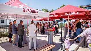 Bild zeigt Veranstaltungsimpression: Schlüsselübergabe am Hamburger Platz in den Außenanlagen, Redner*innen im Vordergrund, Gäste.
