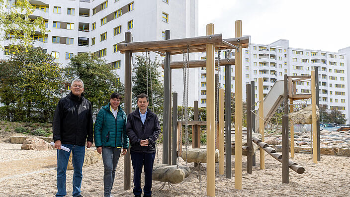 Außenaufnahme zeigt von links nach rechts Karl Wefers, Geschäftsführer von SWUP, Irina Herz von der GESOBAU und Bezirksbürgermeister Uwe Brockhausen links neben einem hölzernen Klettergerüst stehend.