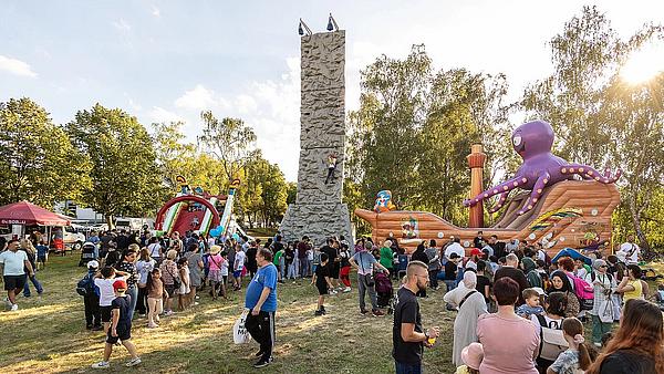 Außenaufnahme zeigt den Kinderspielbereich auf dem Begegnungsfest: ein Kletterturm, eine Hüpfburg in Form eines Piratenschiffs und eine aufblasbare Rutsche.