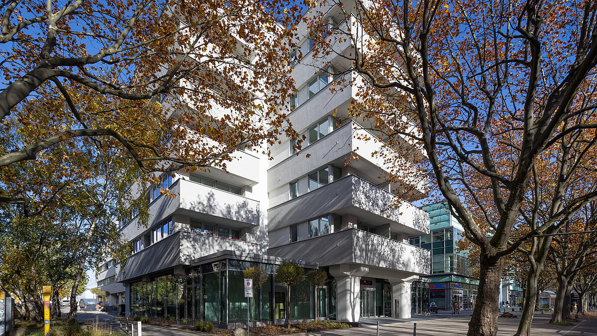 Außenaufnahme zeigt den Wilhelmsruher Damm 142 nach dem Umbau. Aus dem Bürogebäude ist ein helles Wohnhaus für SeniorInnen geworden.