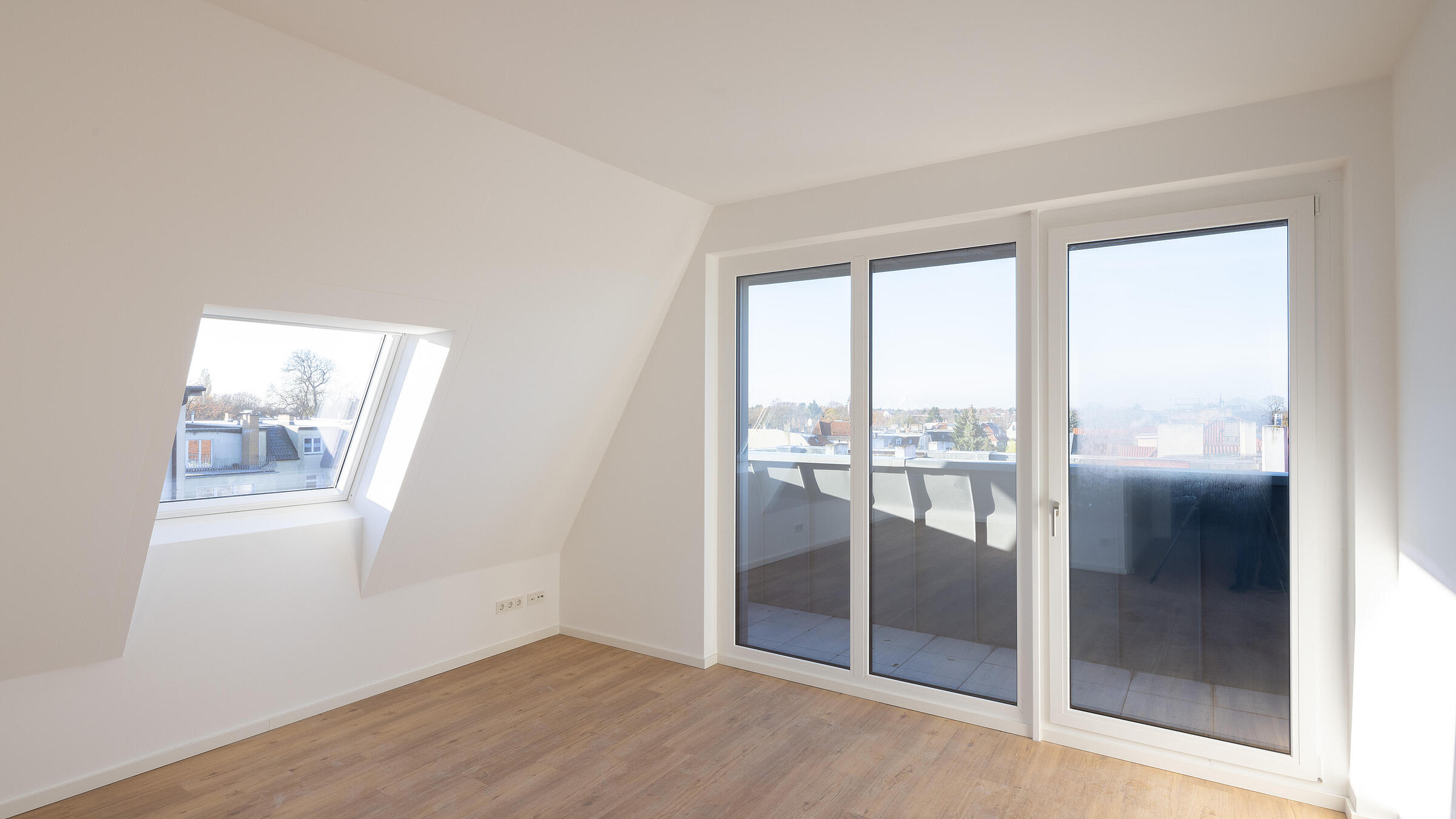 Bild zeigt Musterwohnung im Dachgeschoss der Uhlandstraße 70: Blick ins Wohnzimmer Richtung Balkon.