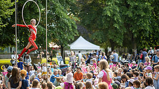 Bild zeigt Artistin am Reifen in der Luft vor Publikum im Schlosspark Schönhausen.