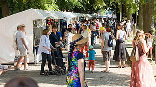 Außenaufnahme zeigt Besucher*innen entlang der Allee.