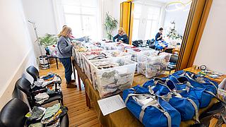 Viele Kisten mit Babykleidung, die von Gesobau-Mitarbeiterinnen sortiert und gepackt werden.
