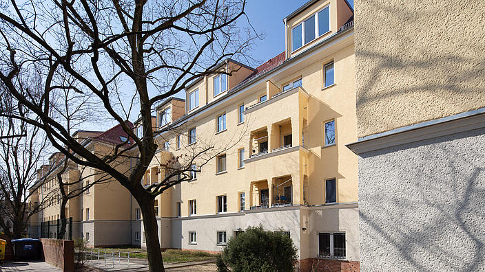 Außenaufnahme zeigt die frisch renovierte Siedlung in der Romain-Rolland-Straße: EIne Häusergruppe mit neu ausgebautem Dachgeschoss. 