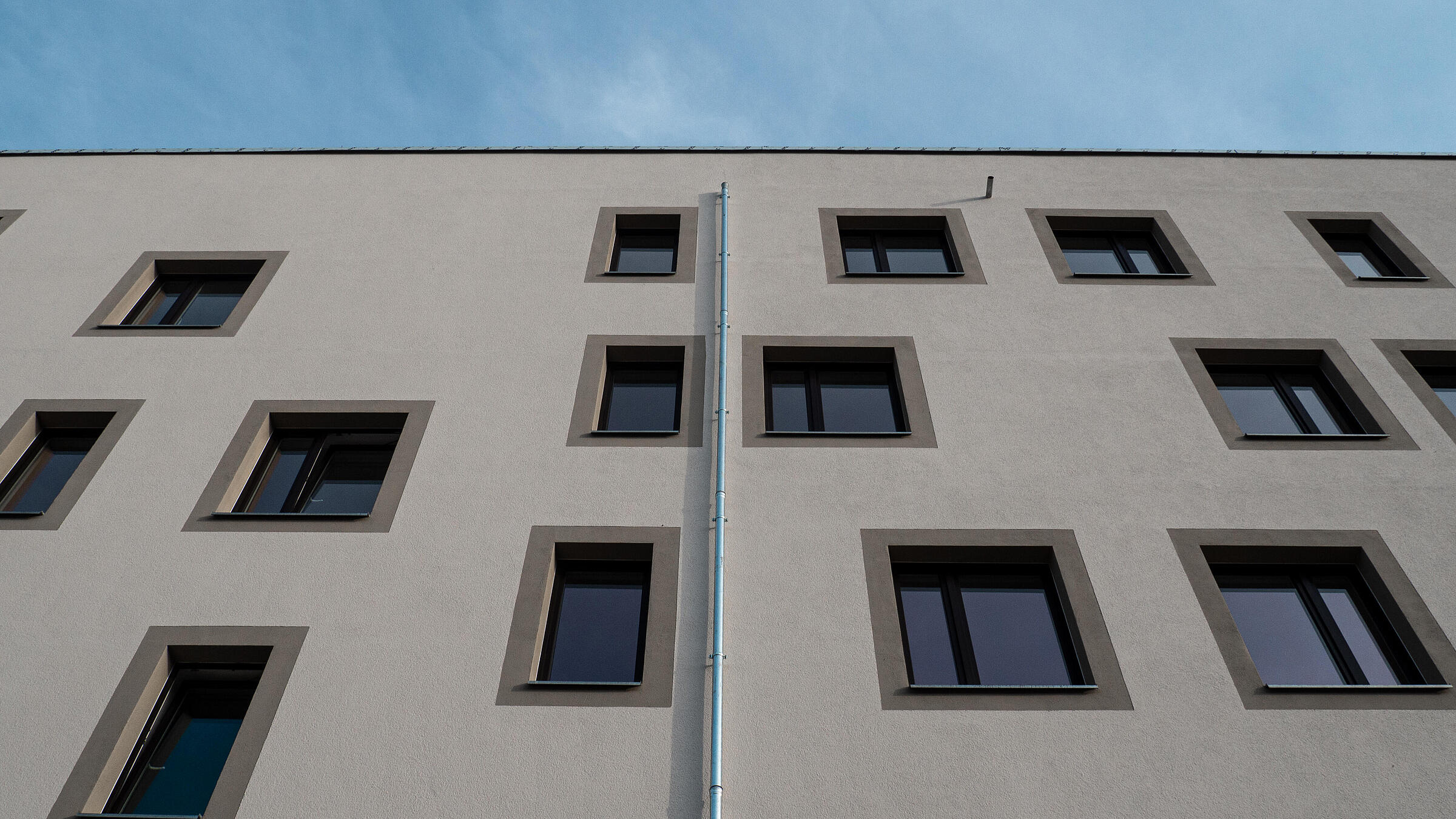 Nahaufnahme einer hellen Wohnhausfassade vor blauem Himmel