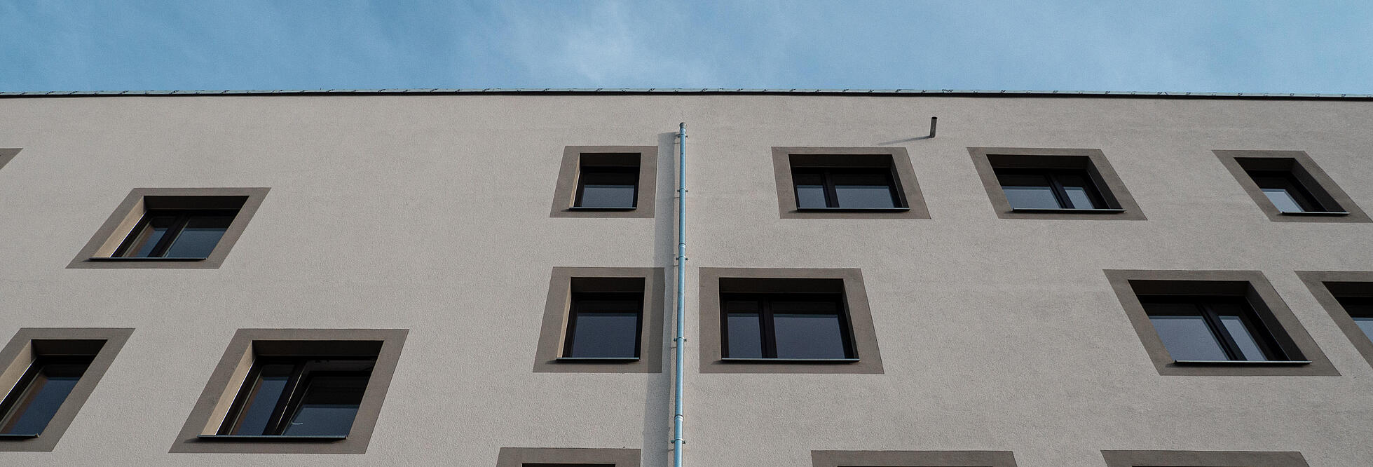 Nahaufnahme einer hellen Wohnhausfassade vor blauem Himmel