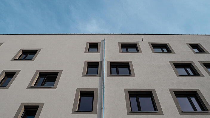 Nahaufnahme einer hellen Wohnhausfassade vor blauem Himmel