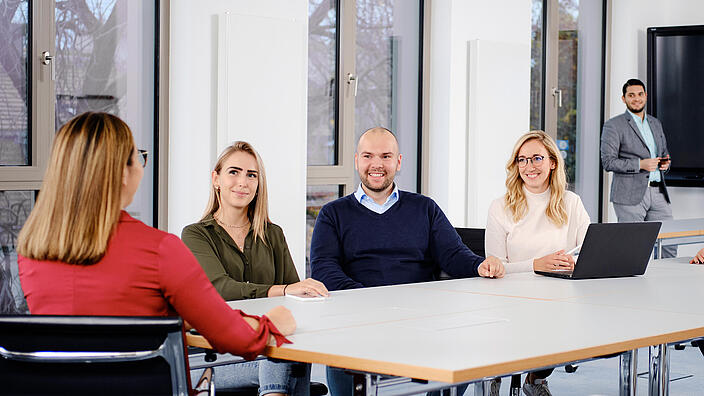 Innenaufnahme zeigt eine Gruppe Mitarbeiter*innen der Gesobau in einem der Konferenzräume am Stiftsweg. Im Hintergrund sichtbar ein Smartboard.