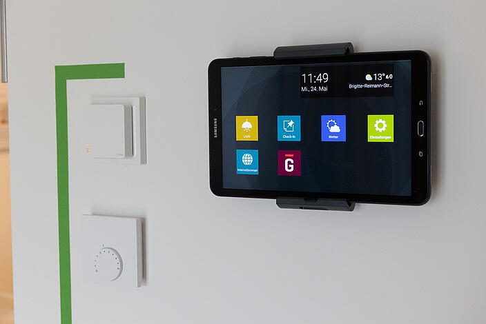 Ein Tablet, das an einer Wand hängt und mit dem sich u.a. Lichtquellen in der Wohnung steuern lassen können.