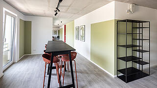 Innenaufnahme zeigt einen Bartisch und -hocker und ein Bücherregal.