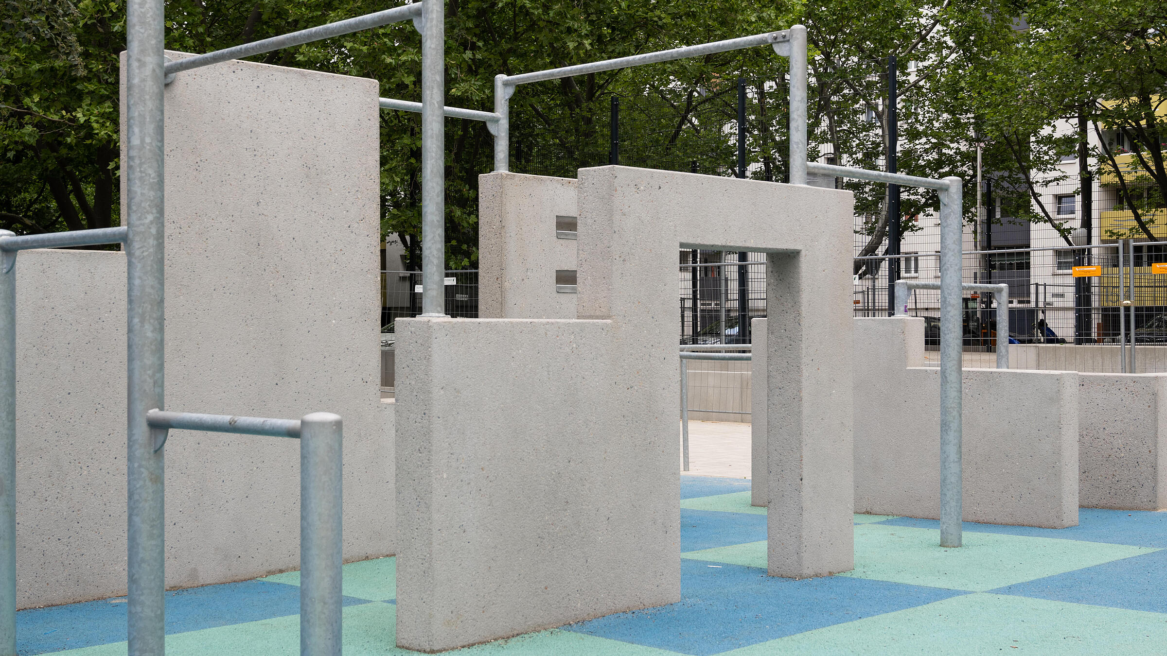 Außenaufnahme des neuen Parkour-Bereichs am Eichhorster Weg. Im Hintergrund Bäume und Mehrfamilienhaus.