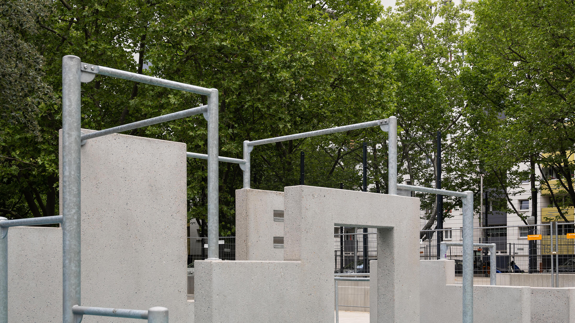 Außenaufnahme des neuen Parkour-Bereichs am Eichhorster Weg. Im Hintergrund Bäume und Mehrfamilienhaus.